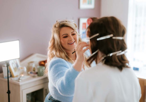 makeup artist doing makeup with bride facing towards her